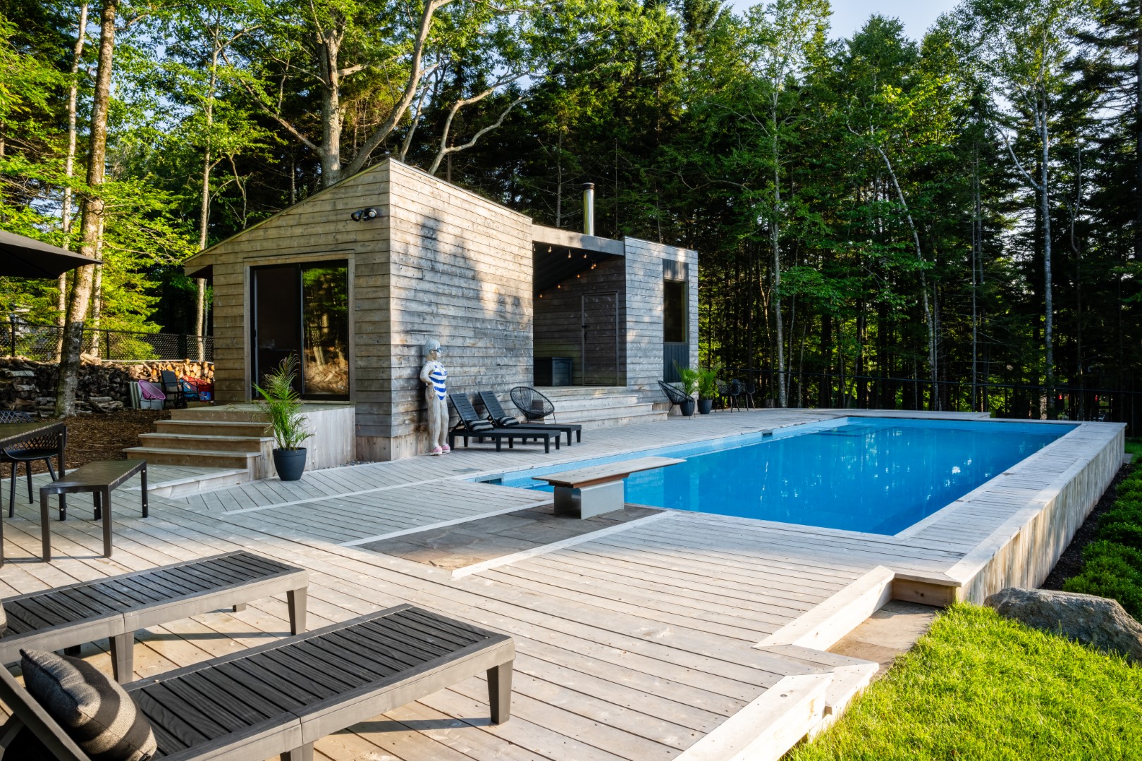 Angled shot of Pool with wooden diving board and modern wood patio in New Brunswick back garden