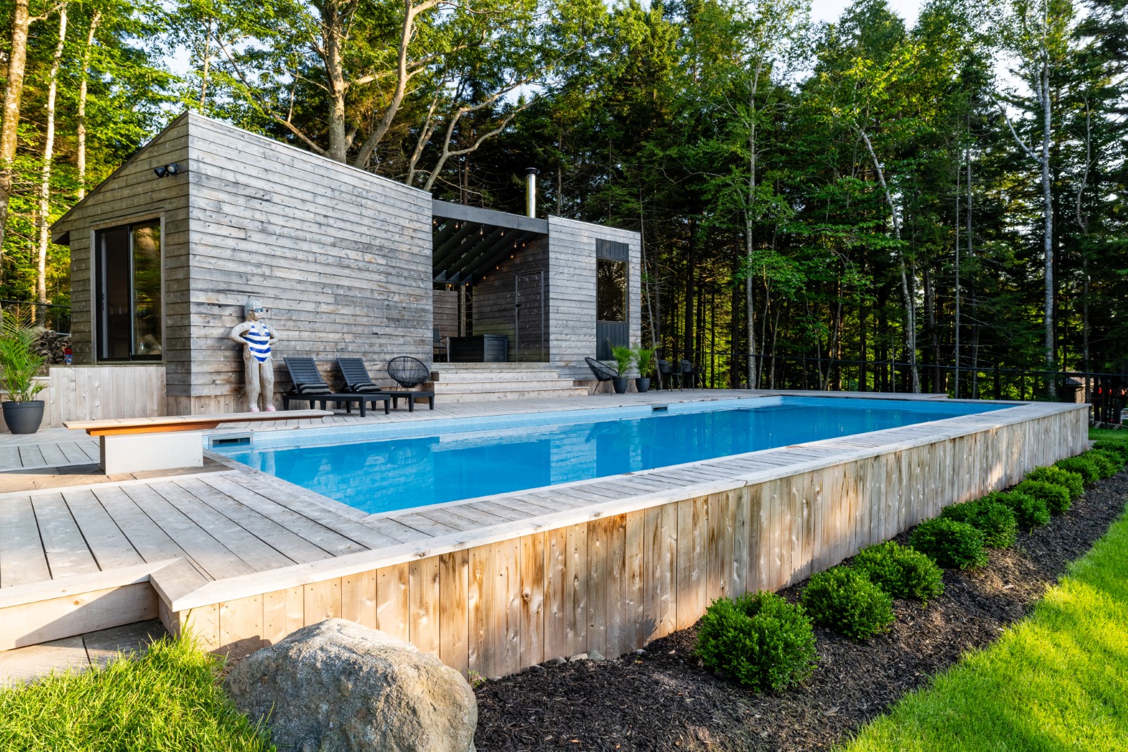 Pool with wooden diving board and modern wood patio added to existing wellness room in New Brunswick