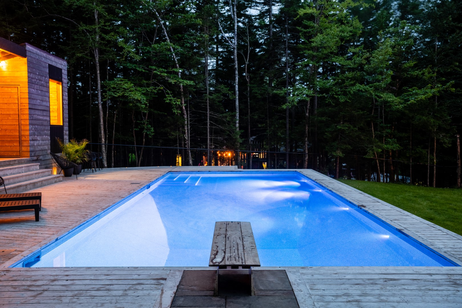Resident swimming pool with wooden diving board and patio in Rothesay
