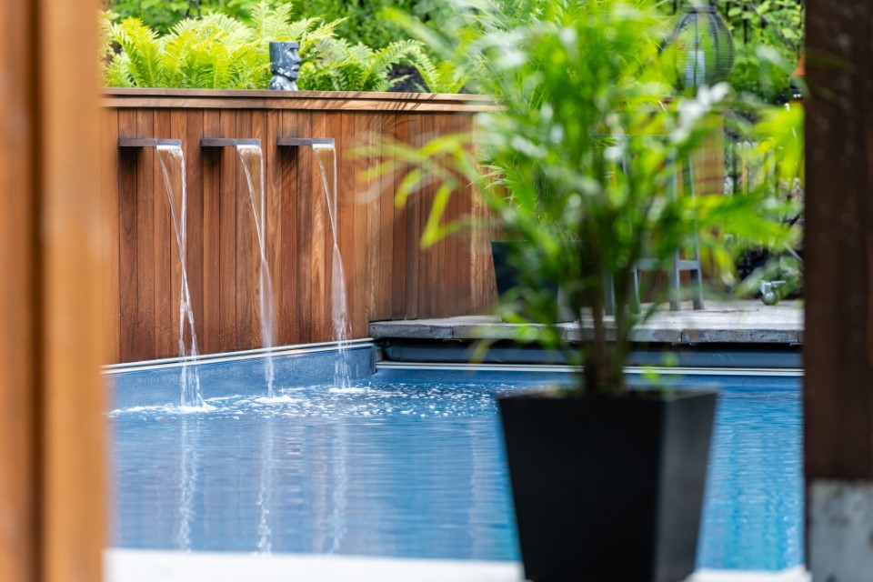 Home swimming pool with triple spout water feature and plants in Lakeburn