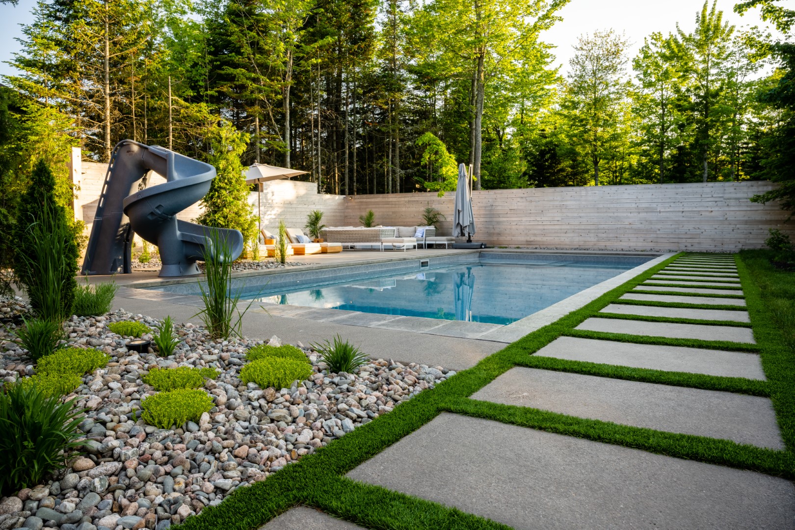 Home swimming pool with tanning ledge and spiral pool slide in Moncton