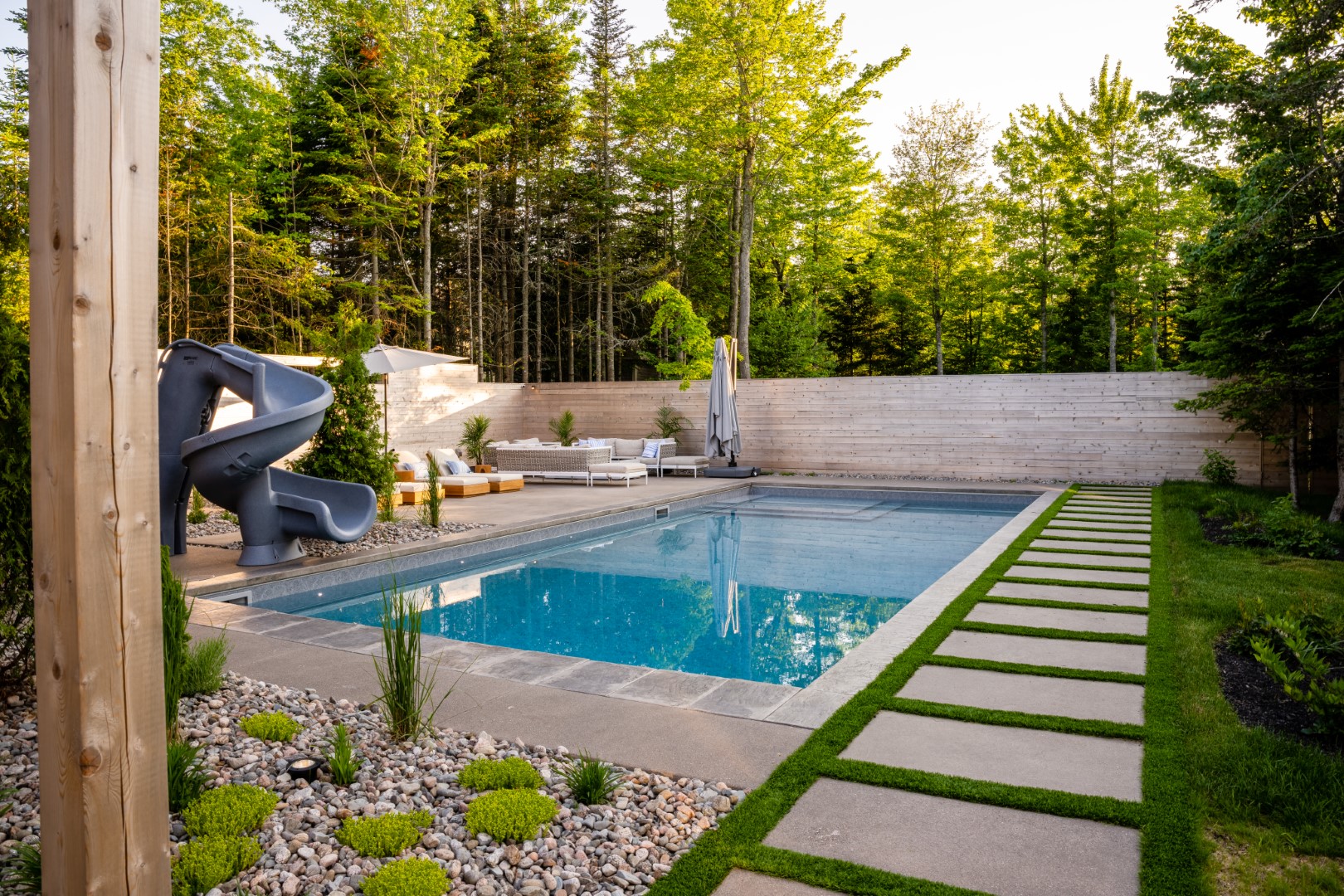 Home swimming pool with tanning ledge and spiral pool slide in Moncton