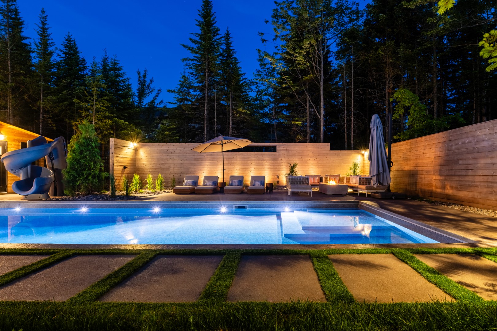 Seating area lit up at night both in garden and pool underwater lighting at Moncton residence