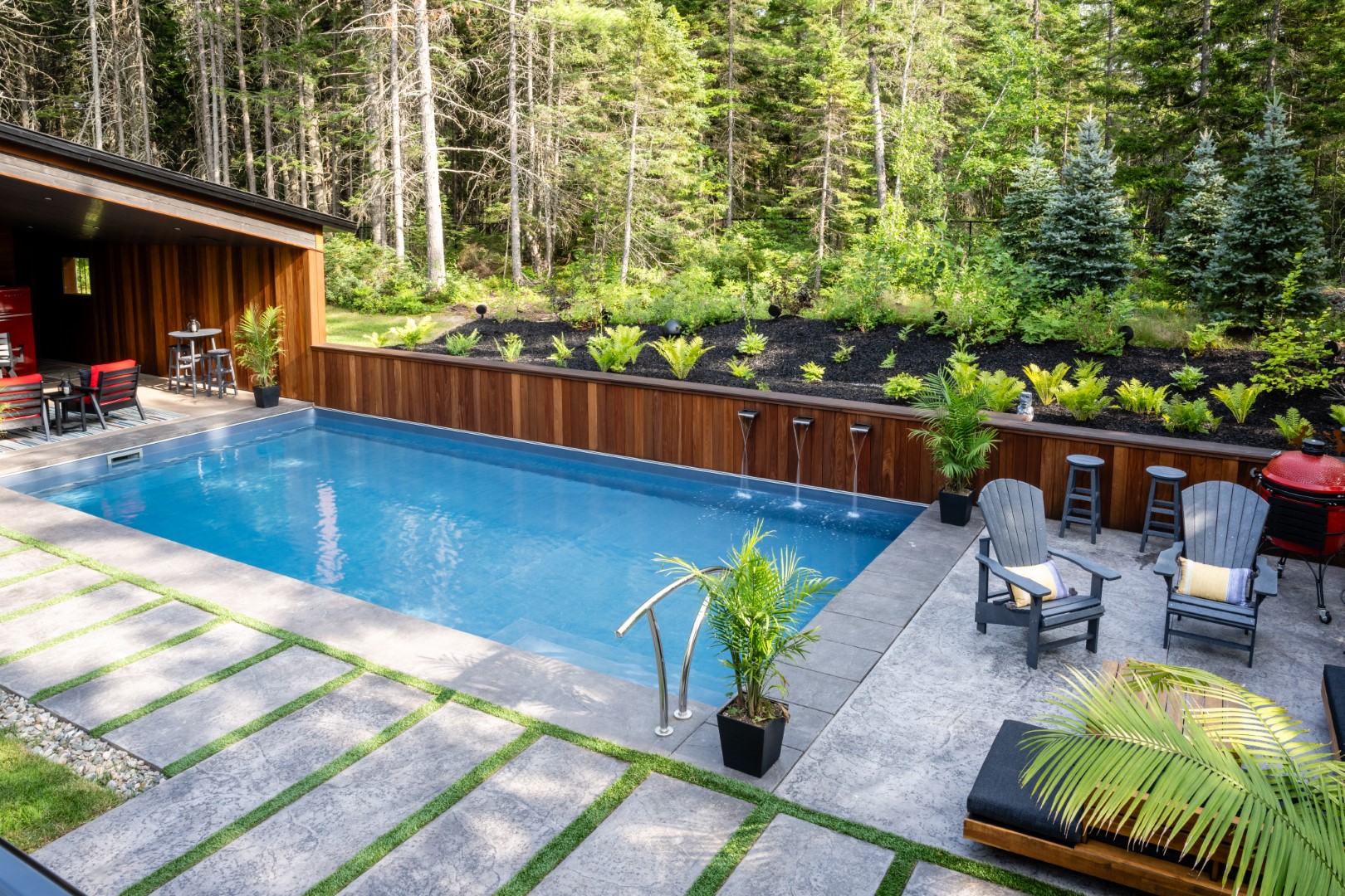 Angled shot of home swimming pool installation in Lakeburn with seating area and triple water spout feature