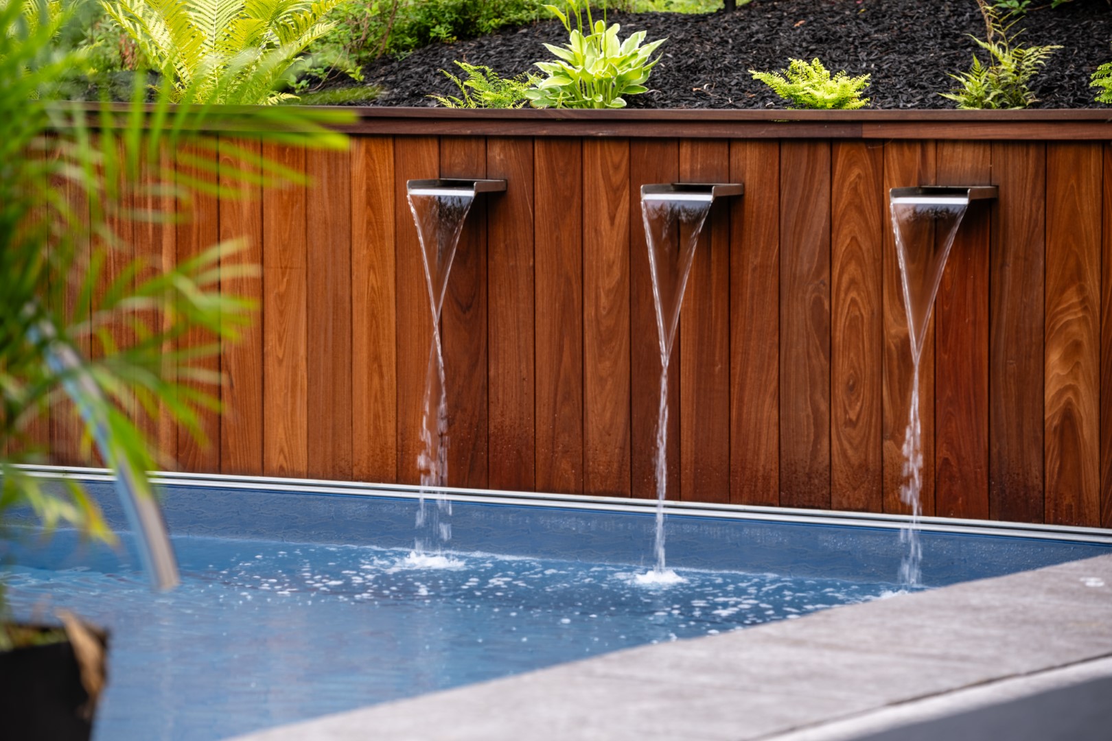 Triple water spout water feature flowing into luxury home swimming pool in Lakeburn, New Brunswick