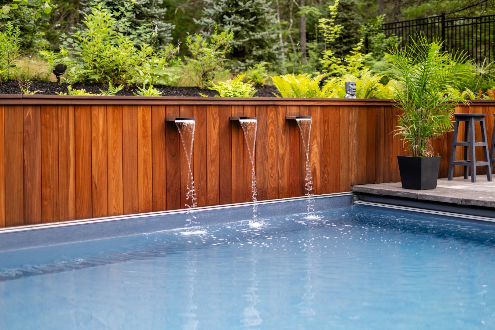 Triple water spout water feature flowing into home swimming pool in Lakeburn