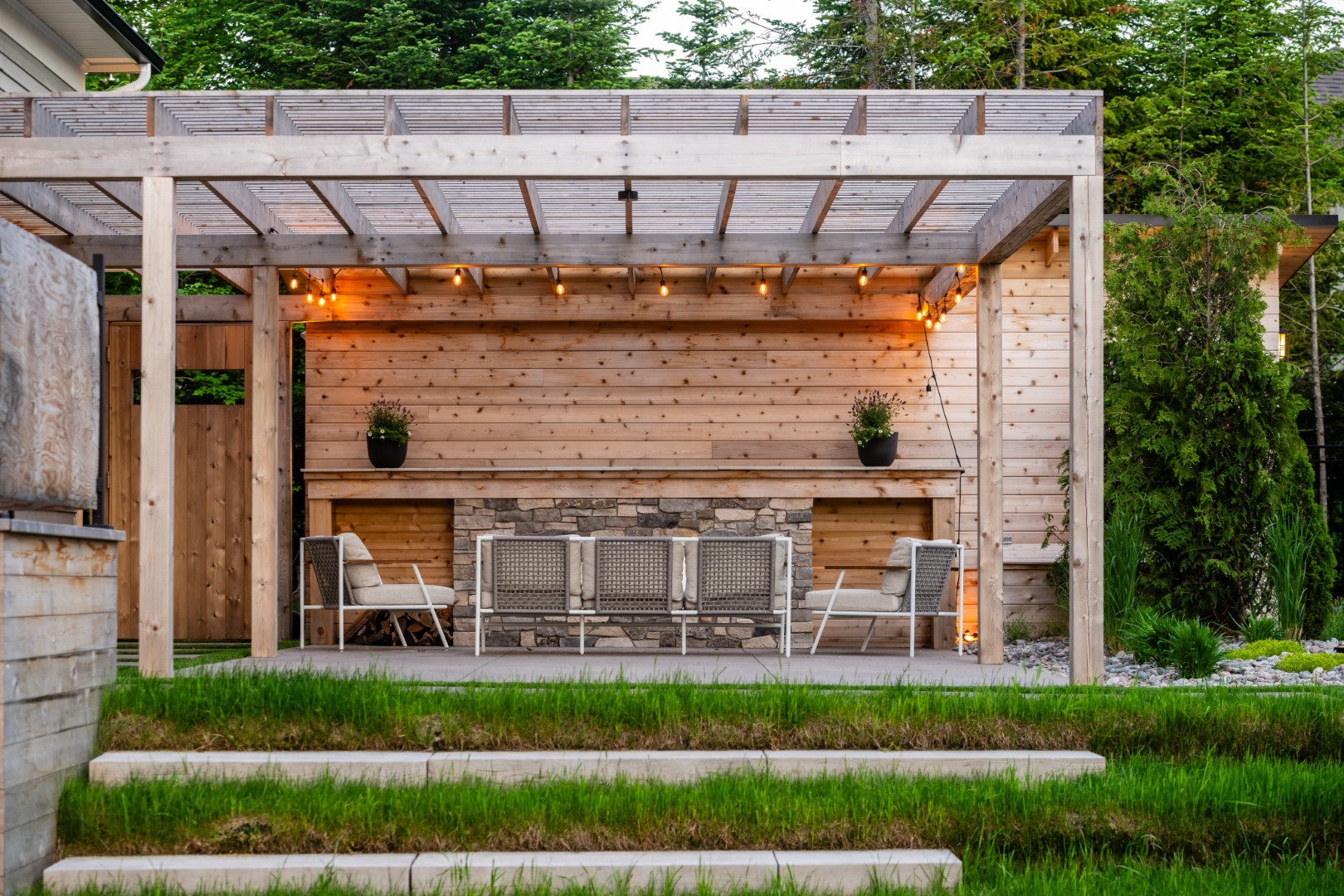 View from side of Pergola with fireplace, attached to pool house with storage and bathroom in Moncton residential property