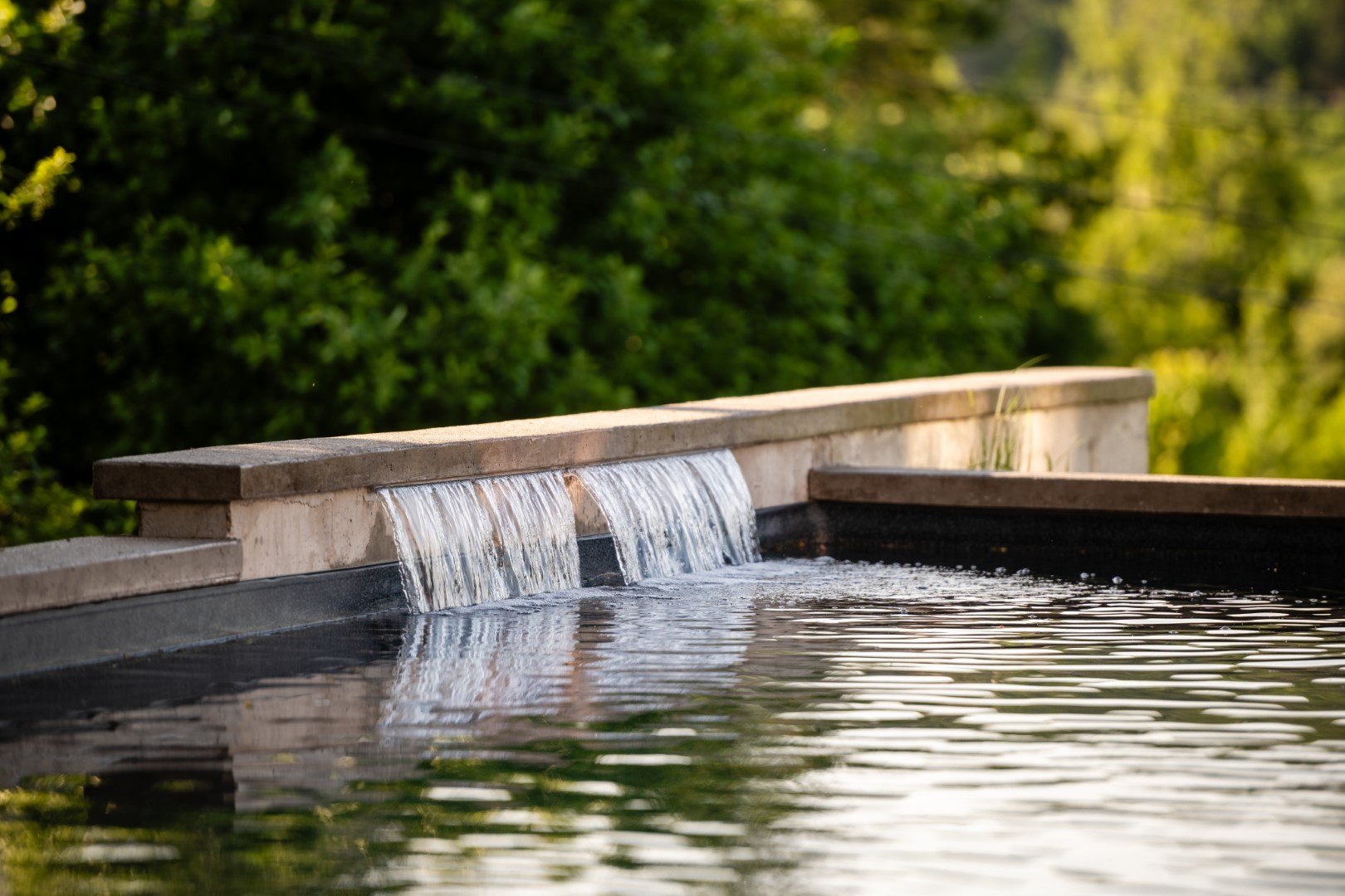 Water feature on edge of home swimming pool installation in a Sussex home