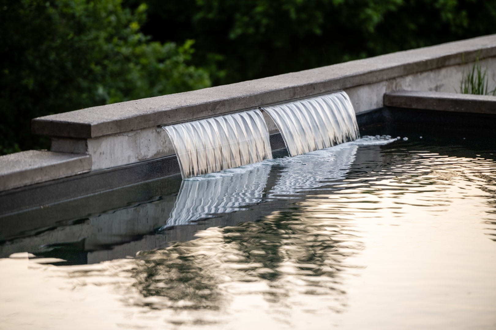 Water feature on edge of home swimming pool installation in a Sussex home