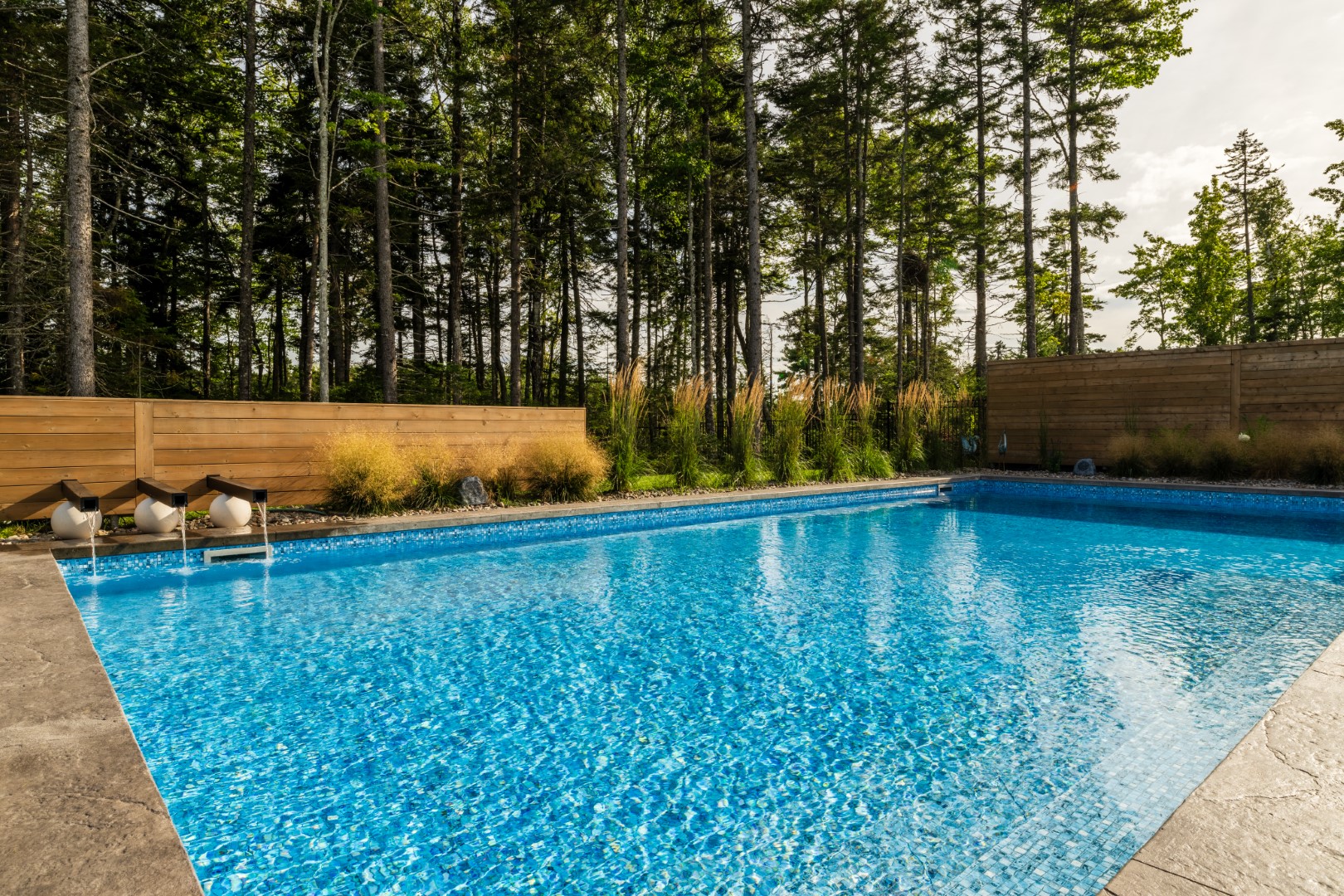 Clear blue water residential luxury pool with water feature for customer in Moncton, NB